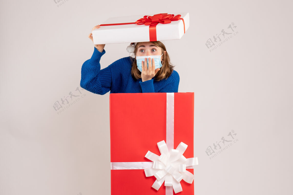 盒子年轻的女人躲在礼物盒里 脸上露出惊讶的白色礼物圣诞节惊喜