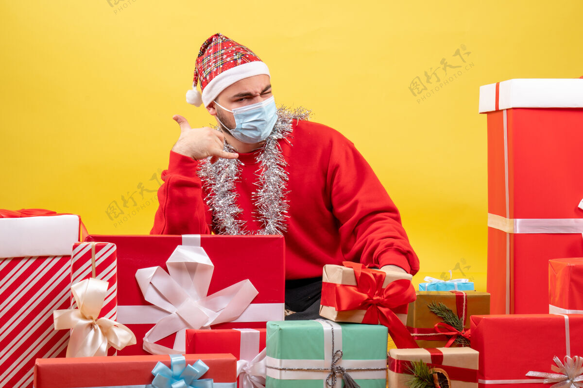人正面图：年轻男性围坐在黄色背景上 戴着面具展示礼物圣诞节周围面具