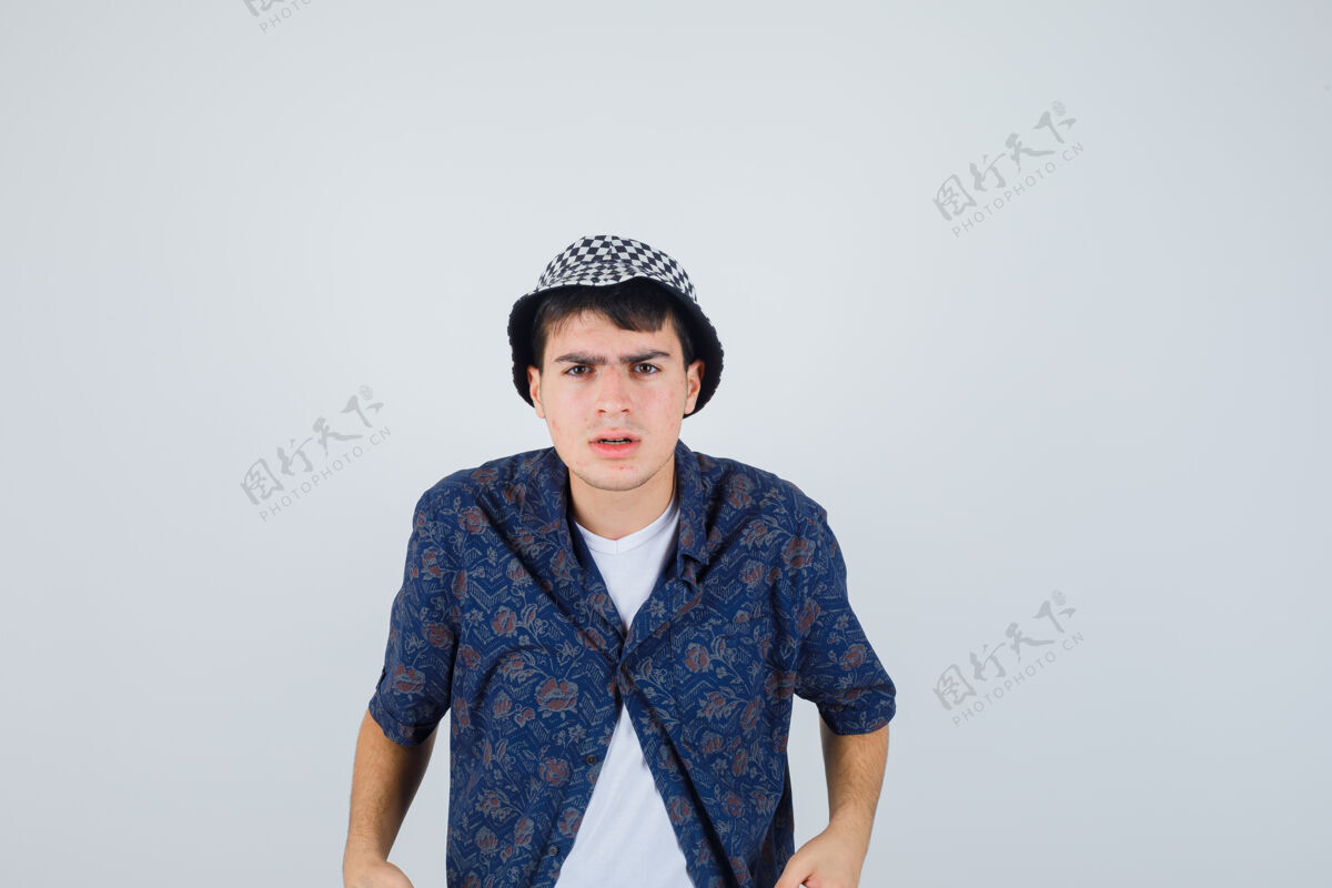 青少年小男孩笔直地站着 穿着白色t恤 花衬衫 帽子做鬼脸 看上去很严肃正视图休闲帽子青年