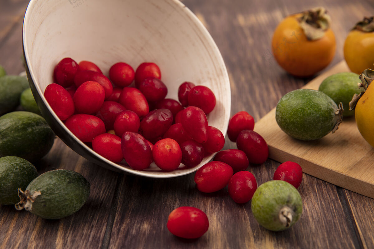 樱桃顶视图：红色酸涩的山茱萸樱桃从碗里掉出来 柿子和飞珠被隔离在木墙上景落肥肉
