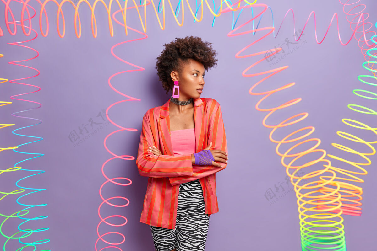 五彩表情严肃的漂亮模特 时尚的卷发 自信的站姿 移开视线 穿着时髦的服装派对紫色非洲