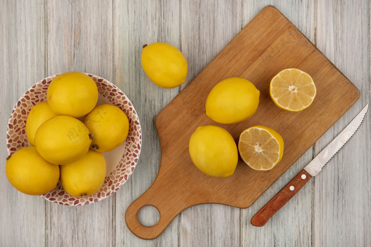 新鲜一个碗上的圆形柠檬的俯视图 柠檬被隔离在木制的厨房板上 刀子放在灰色的木制墙上刀木材圆形
