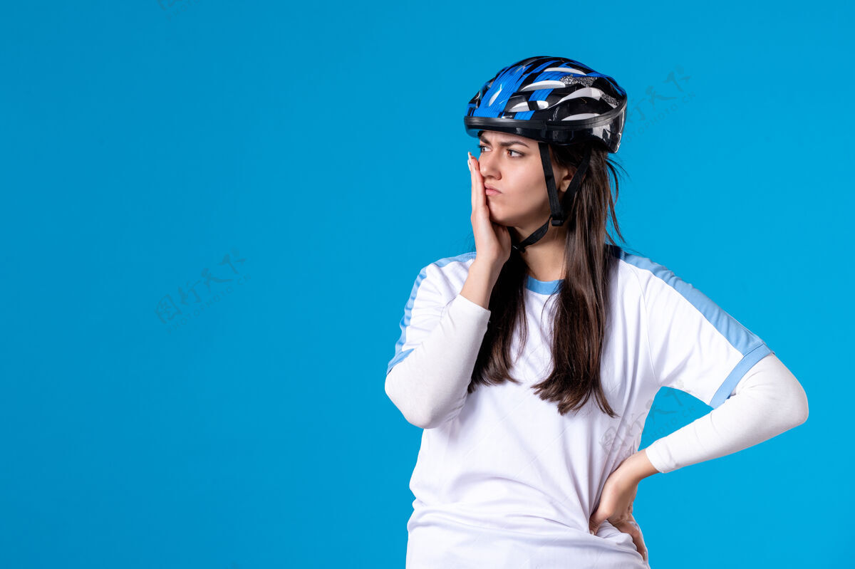 蓝色前视图穿着运动服的年轻女性 蓝色墙上戴着头盔人前面运动