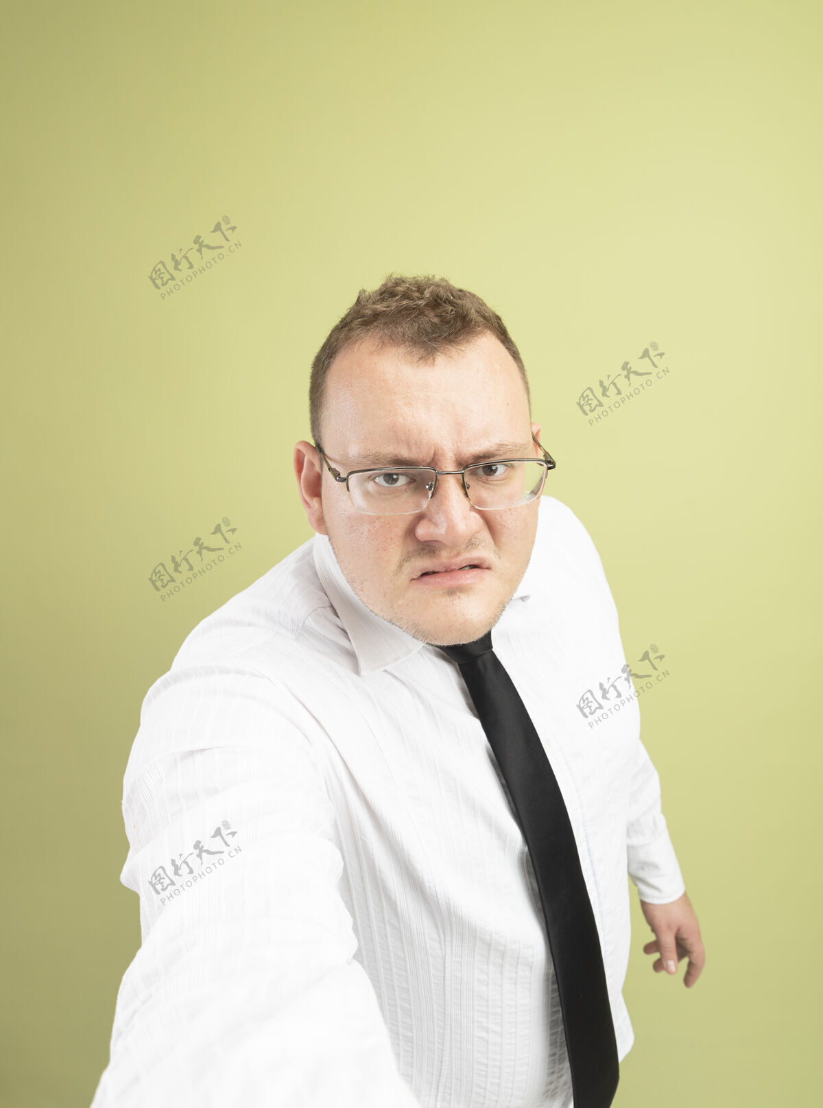 穿一个戴着眼镜打着领带的未被释放的成年斯拉夫人看着相机 向橄榄绿背景上孤立的相机伸出手来成人领带不愉快