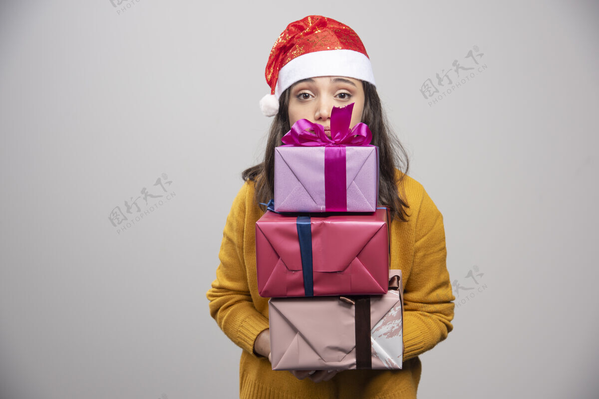 女性微笑的戴着圣诞帽的女人手里拿着礼品盒人冬天表情