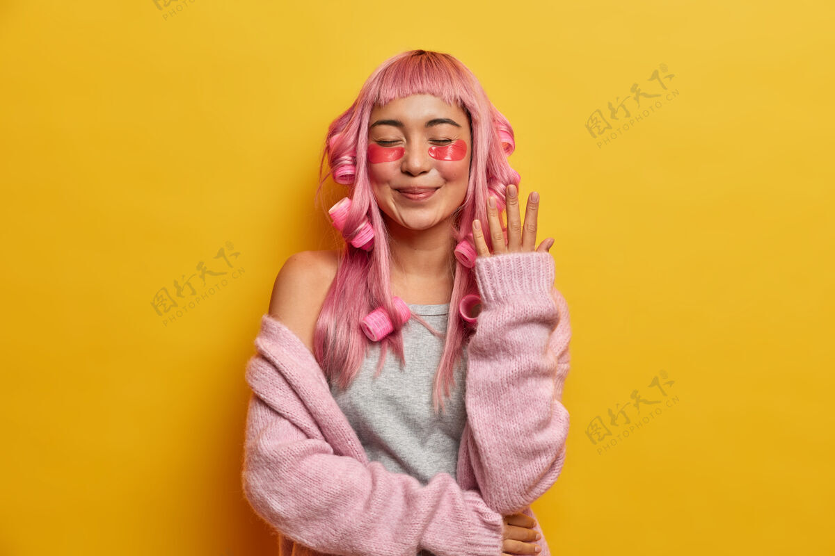 粉色假发满脸笑容 满头粉红头发 涂着滚轴和美容垫 穿着玫瑰色毛衣的女人 享受着自己的闲暇时光补丁粉色头发美容