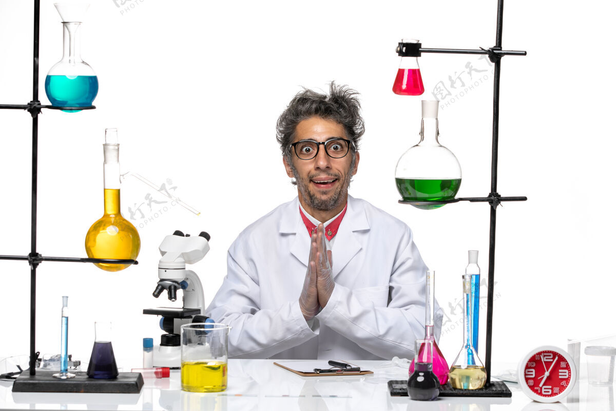 专业人员正面图穿着白色医疗服的中年化学家拿着溶液坐着溶液前台办公桌