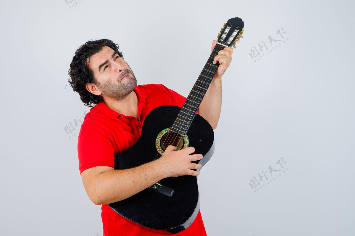 年轻帅哥穿着红色t恤弹吉他 面带沉思 俯瞰前方商业玩成年人