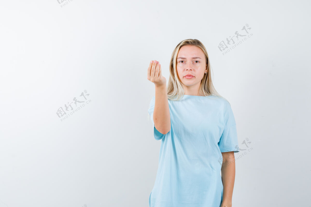 夏天一个金发女孩穿着蓝色t恤展示着意大利的姿态 看起来很严肃 正前方的风景前面肖像手势