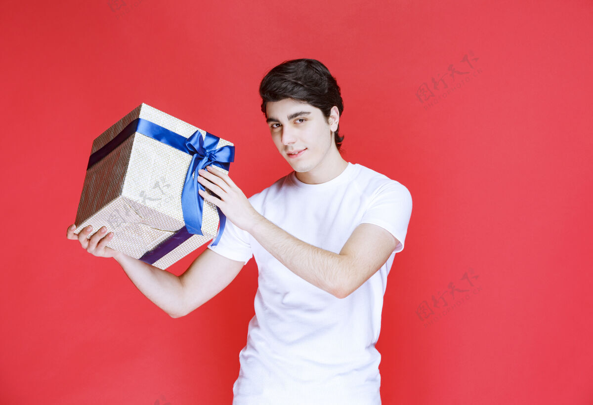 人类一个男人双手拿着一个包着蓝丝带的白色礼盒意外快乐紧身衣