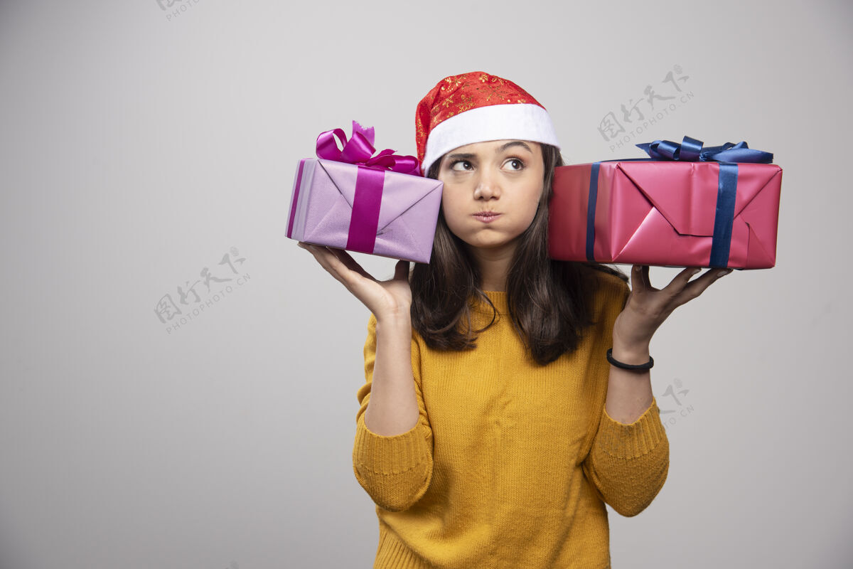 帽子带着圣诞礼物的戴圣诞帽的年轻女子模型女性圣诞老人