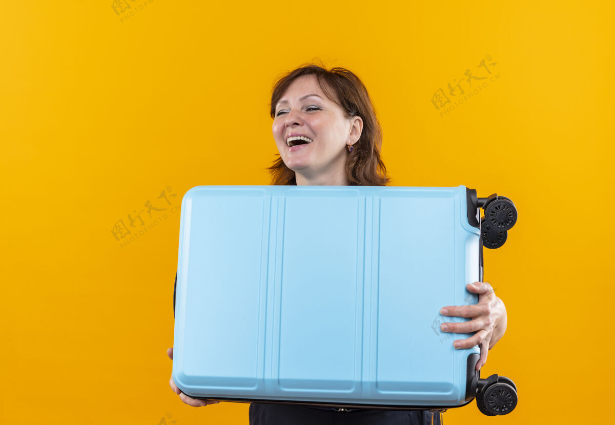 女人微笑的中年旅行家女子拿着手提箱上孤零零的黄色手势表情手提箱
