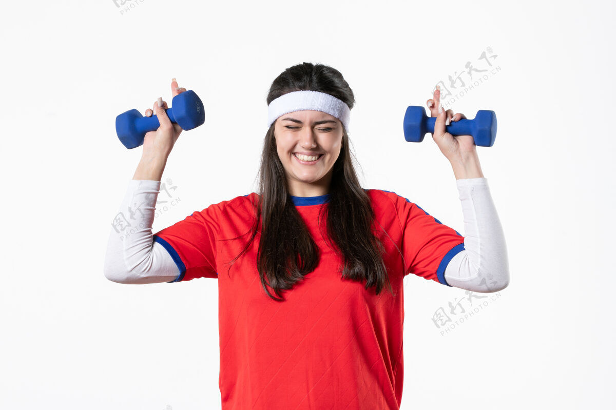 人正面图微笑的年轻女性穿着运动服 用哑铃锻炼身体球员前面视图