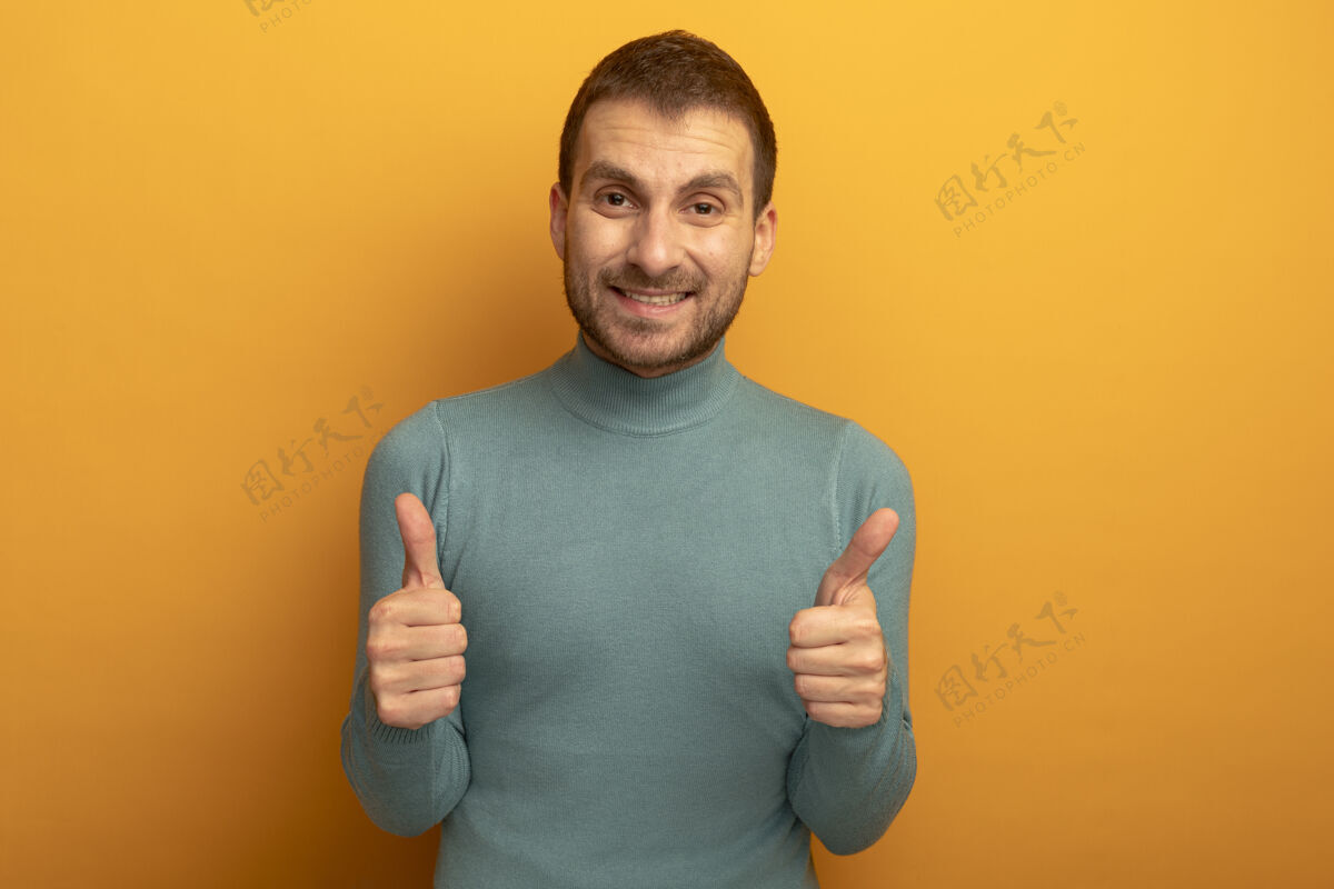 拇指笑容满面的年轻人看着前面竖起大拇指孤立地站在橙色的墙上公民站着衣服