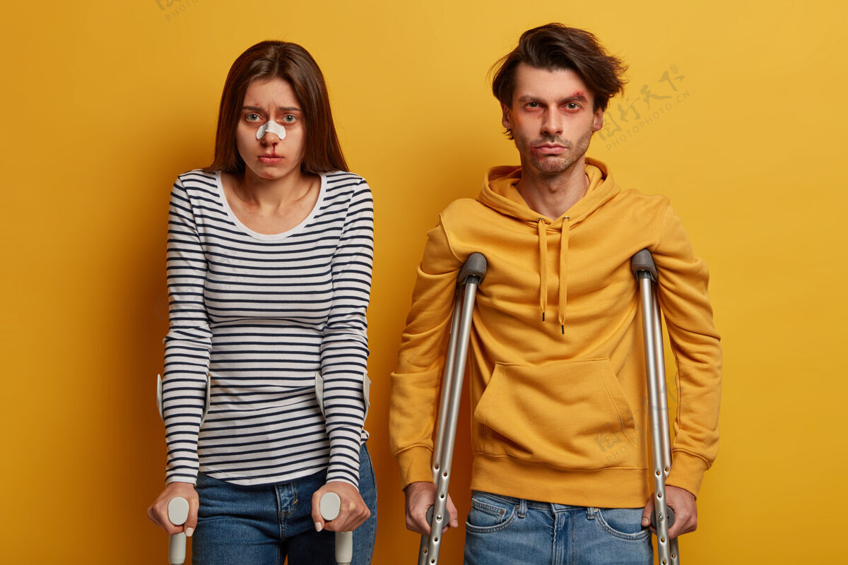 压力不幸的夫妇出了事故 饱受痛苦的感情和各种创伤 拄着拐杖站在一起 被隔离在黄色的墙上意外保险和医疗理念痛苦女人受害者