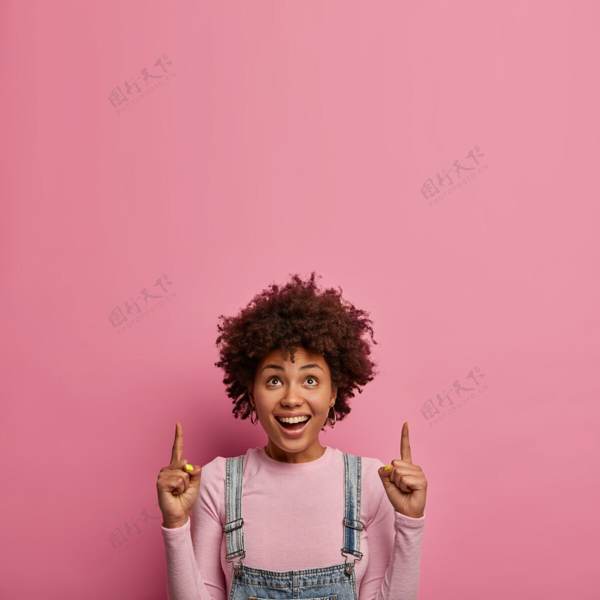 促销上面是一个快乐的黑人女性的垂直镜头 展示了令人敬畏的复制空间 有愉快的面部表情 露出洁白的牙齿 穿着随意 在商场或商店促销商品指示器发型非洲
