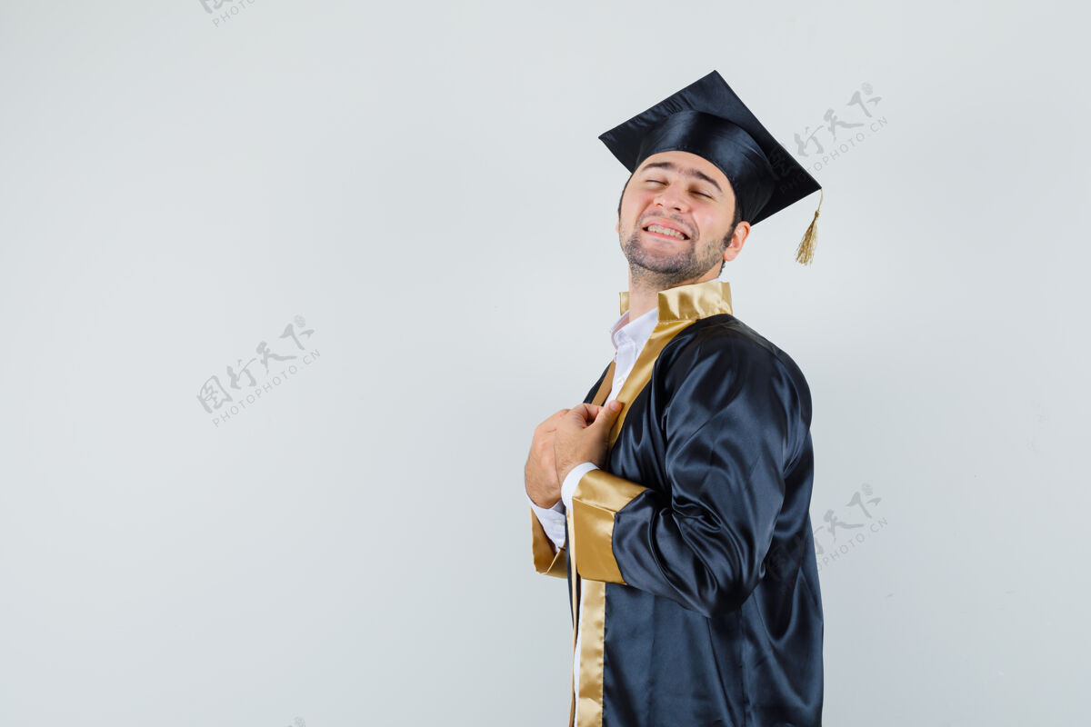 礼服年轻的男性拿着他的毕业礼服 看起来很平静休闲制服毕业