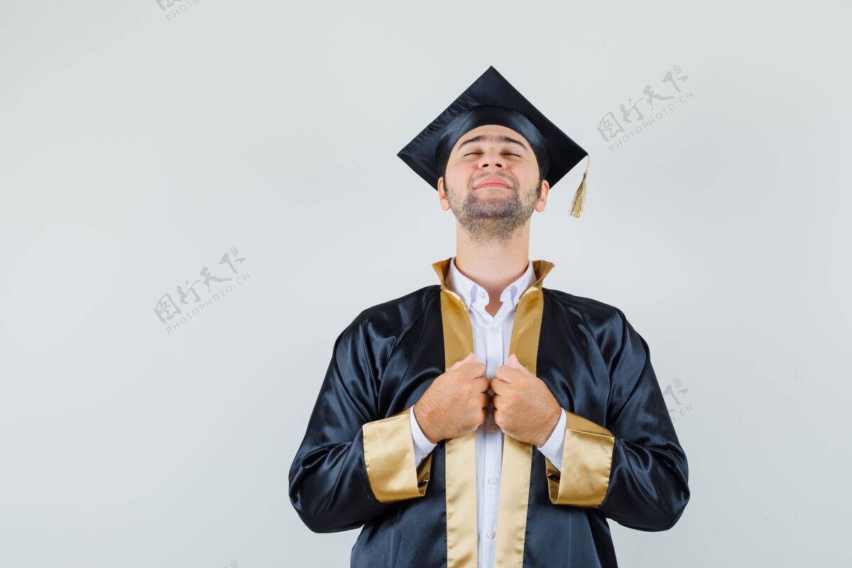 年轻年轻的男学生手牵着毕业服上的长袍 看上去很平静 正对着前方模特男人休闲