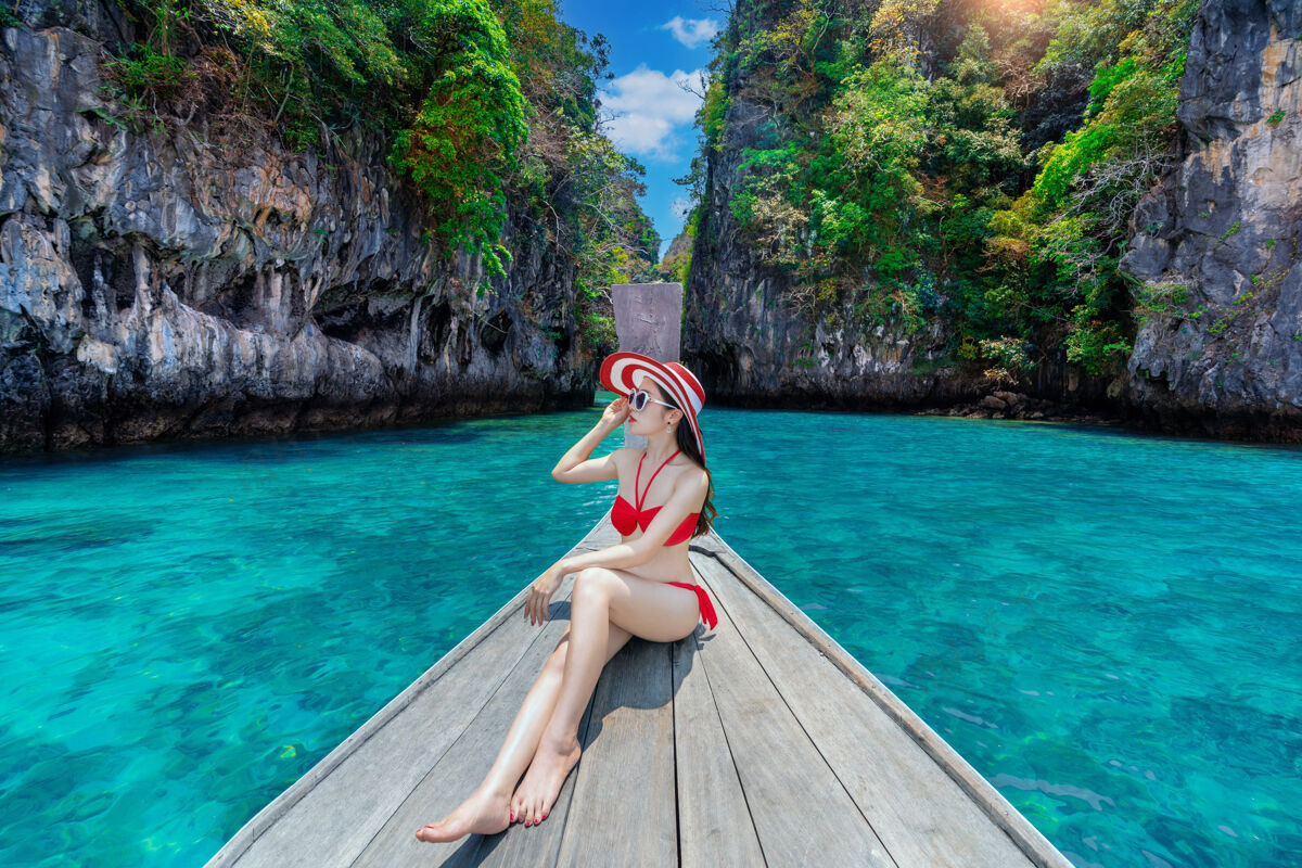 泻湖泰国高鸿岛 一个穿着红色比基尼的漂亮女孩在船上海洋海滩放松