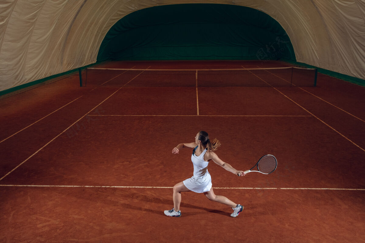 运动年轻的职业女运动员在运动场的墙上打网球女人练习女