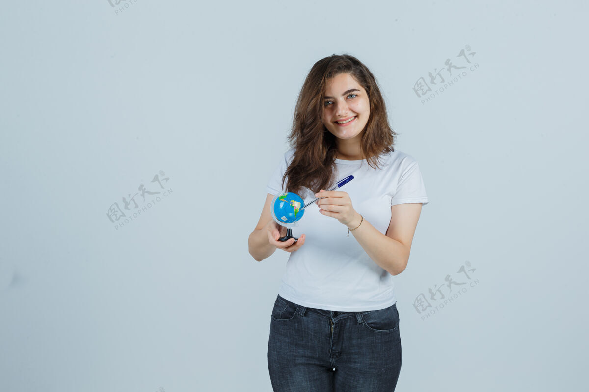 人照片中的年轻女孩拿着钢笔站在地球仪上 穿着t恤 牛仔裤 看上去很开心头发年轻魅力