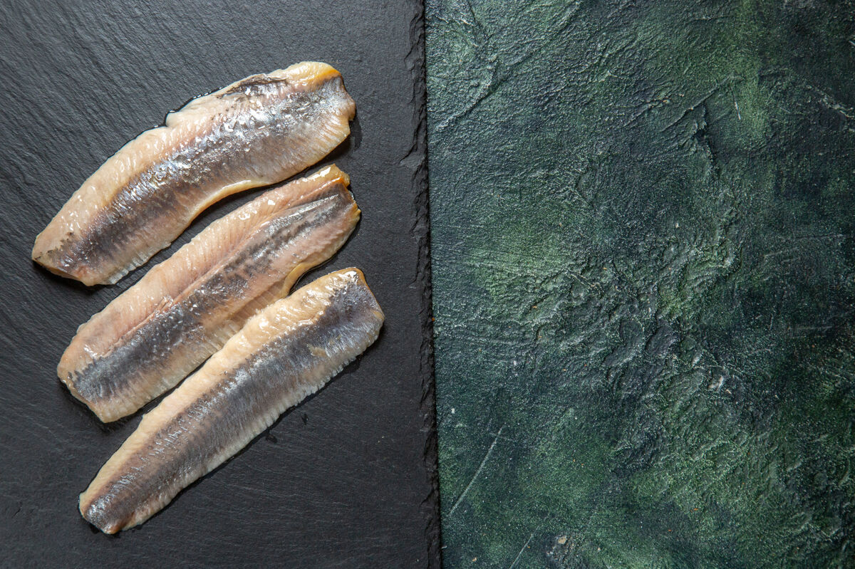 木材新鲜的生切碎鱼的顶视图在黑色的木制切肉板的右侧混合色背景上右背景顶部