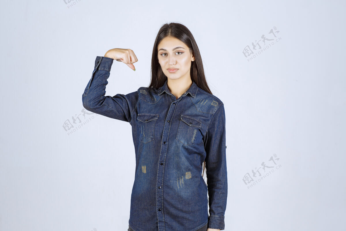 聪明穿着牛仔衬衫的年轻女子展示了她的手臂肌肉年轻锻炼强壮