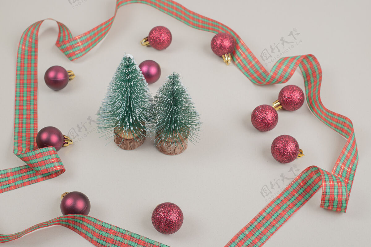 玩具两棵圣诞小树 白色表面有节日的蝴蝶结圣诞弓圣诞弓圣诞球