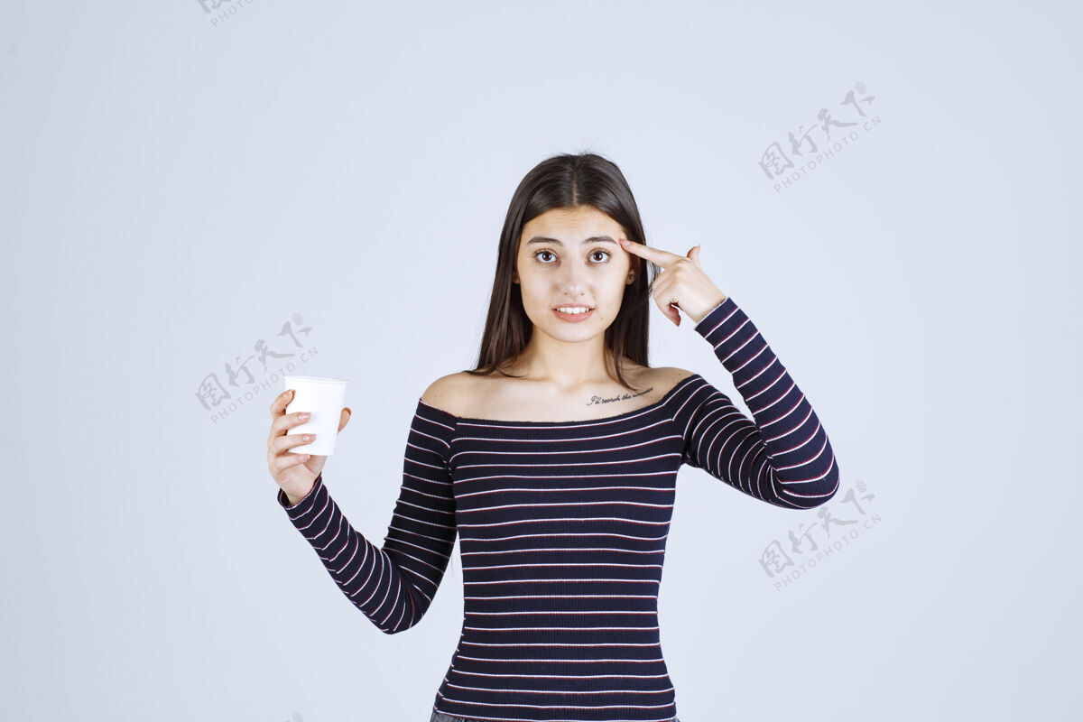 女人穿着条纹衬衫的女孩拿着一个塑料咖啡杯在思考品味计划职员