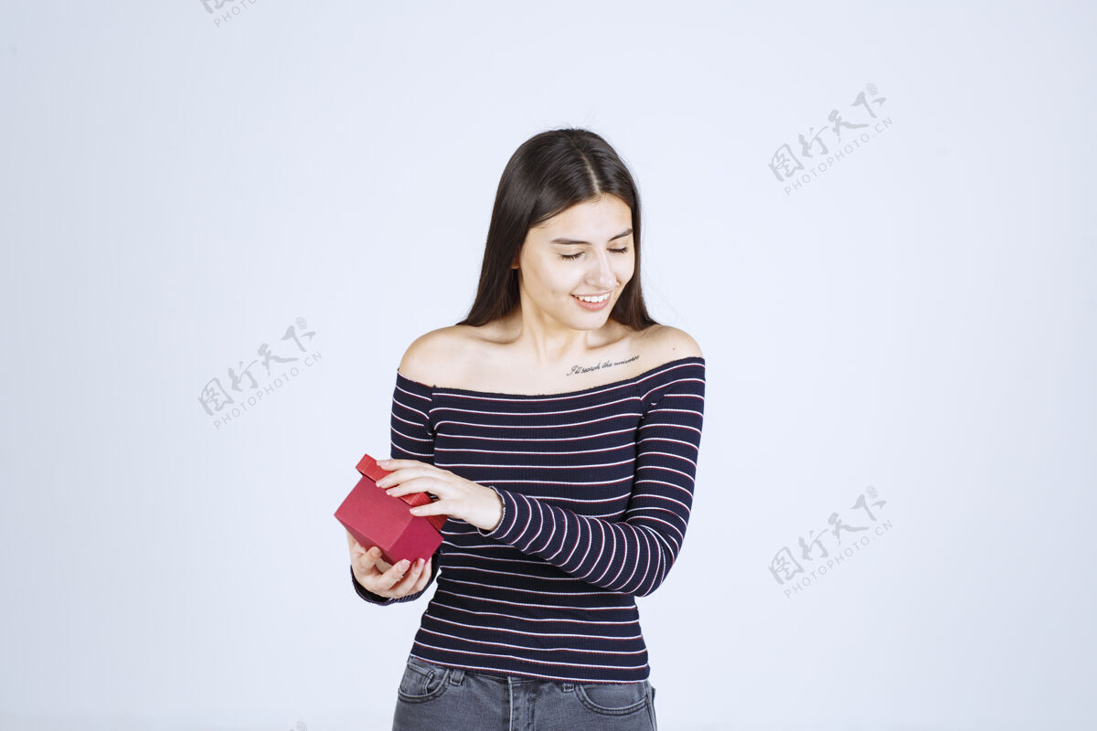 女人穿条纹衬衫的女孩打开一个红色的礼盒 很高兴聪明积极休闲