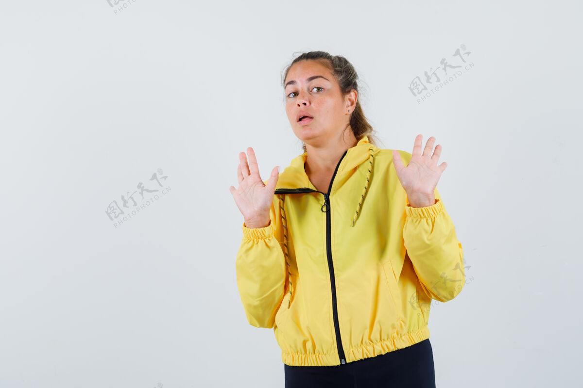 人一个穿着黄色雨衣的年轻女子举手表示拒绝 看起来很不情愿头发休闲脸