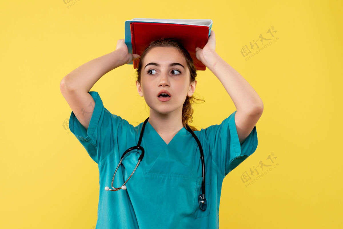 女人正面图女医生穿着医用衬衫手持纸条 彩色病毒健康情感covid-19大流行制服黄色便条剪贴板