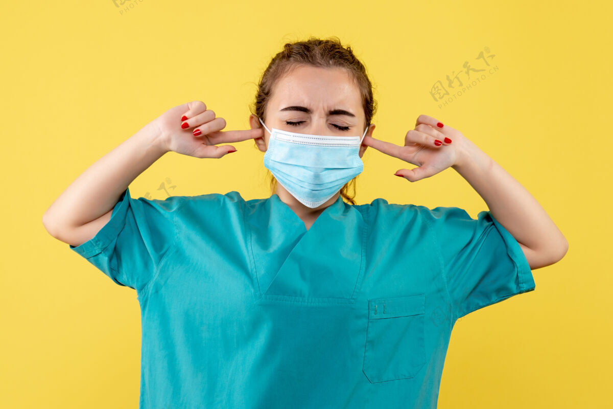 黄色正面图女医生穿着医用衬衫 戴着口罩捂着耳朵 涂上大流行性健康病毒covid-19制服女人女医生人