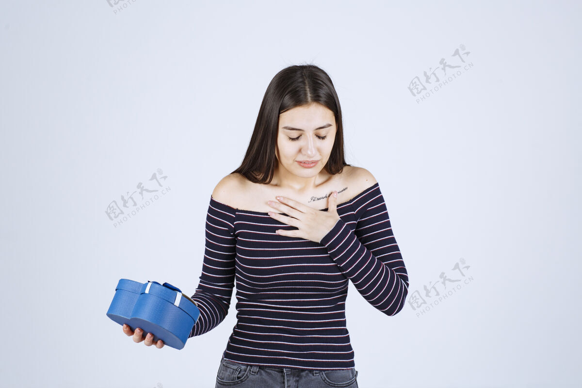 女人穿着条纹衬衫的女孩手里拿着一个蓝色心形礼盒 激动不已恐惧困惑意外