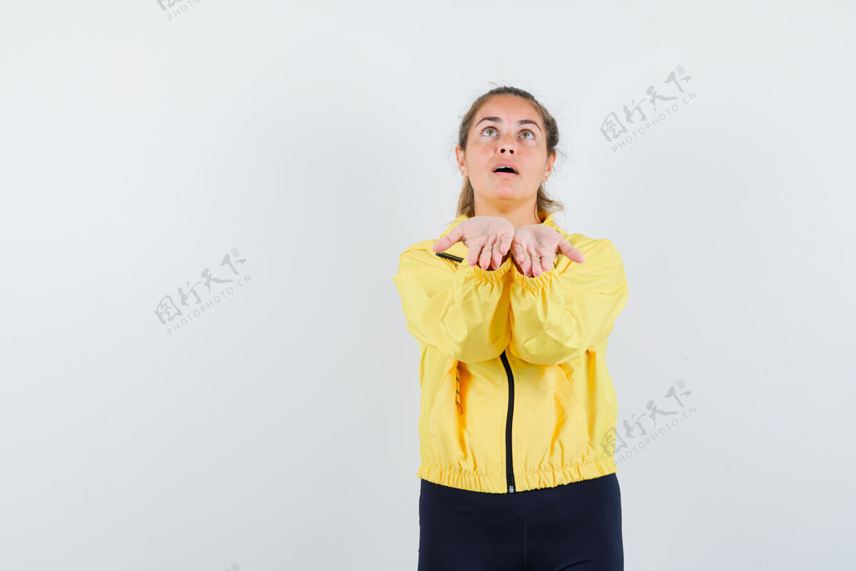 脸一个金发女人 手上拿着一件想象中的东西 穿着黄色棒球服和黑色裤子 看起来很专注肖像焦点模特