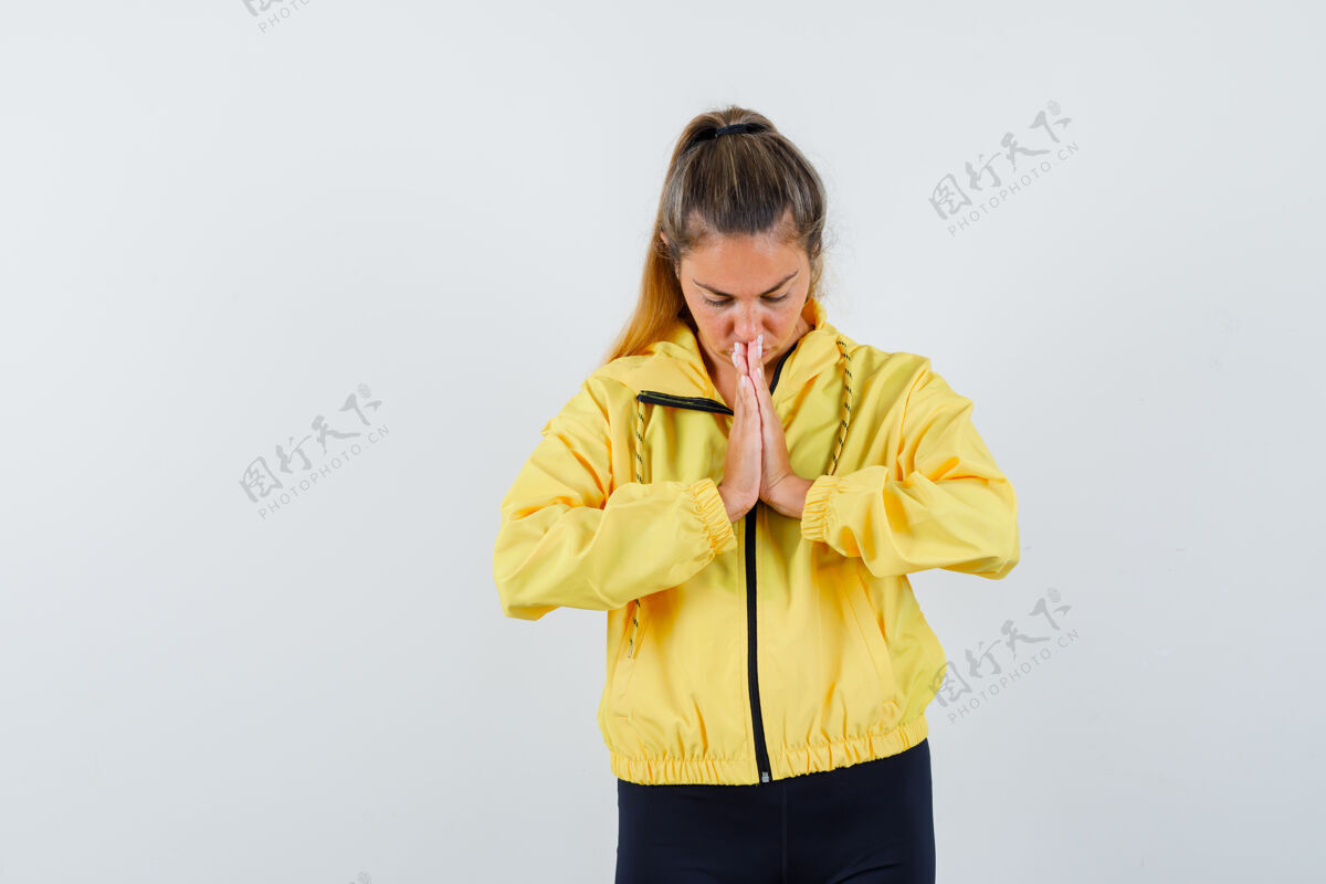 肖像穿着黄色棒球服和黑色裤子的金发女人站在祈祷姿势 看起来很专注干净漂亮夹克