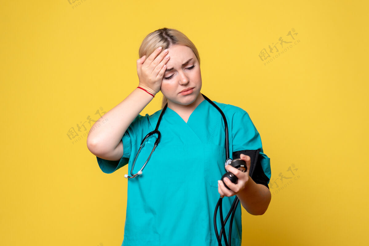 医生前视图女医生正在检查她的血压 医生科维德-19医院护士病毒救护车听诊器黄色女
