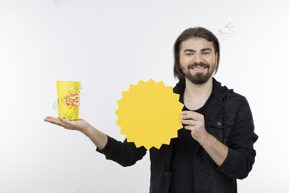 零食大胡子男人拿着一桶爆米花和纸太阳模型食物男孩
