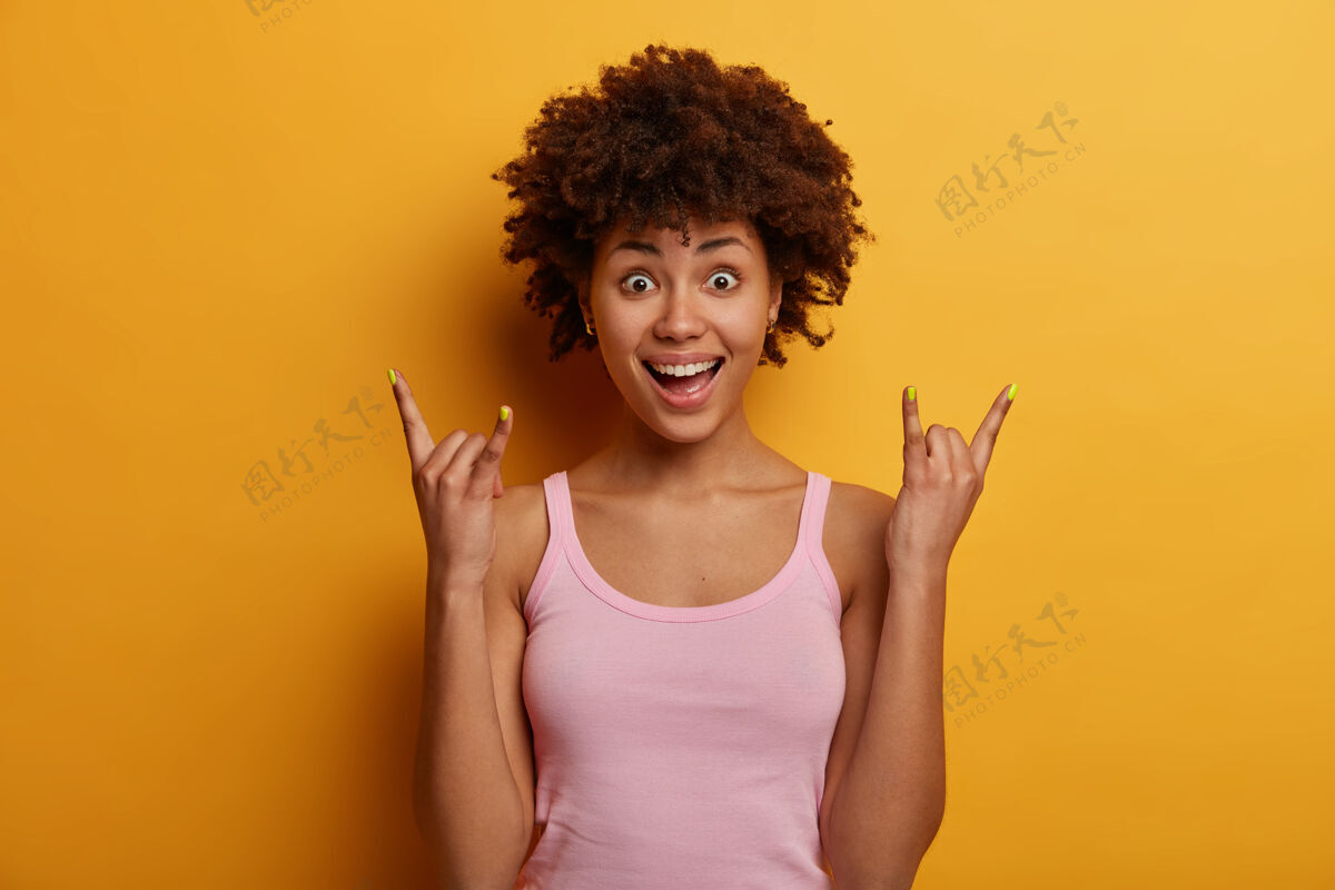 姿势惊讶的非裔美国女人做摇滚手语牙齿个人笑