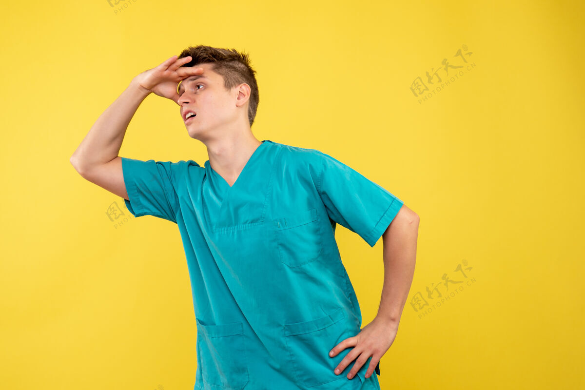 正面黄色墙壁上穿着医疗服的男医生的正视图人运动装西装