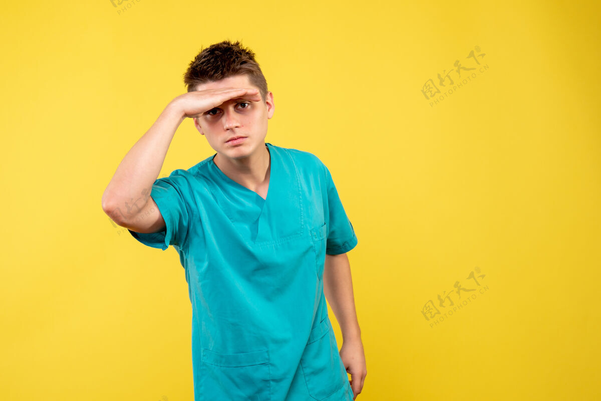 微笑黄色墙上穿着医疗服的男医生的正视图男医生医院病毒