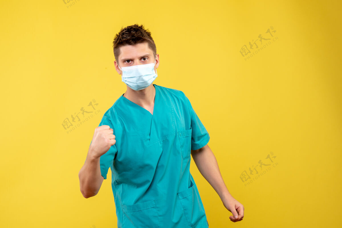 面具黄墙上的男医生穿着医疗服 戴着无菌口罩医学医院男性