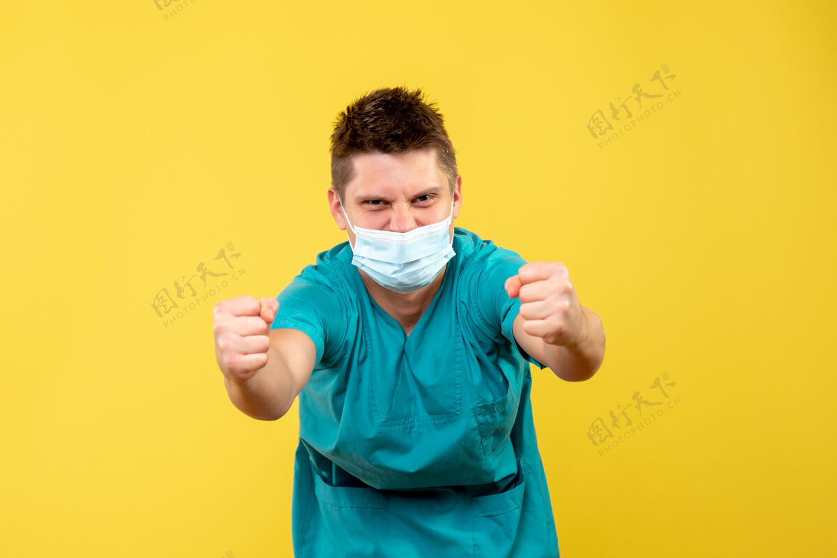 男医生身着医疗服 戴着无菌口罩的男医生正站在黄色的墙上欢呼雀跃快乐绝育男孩