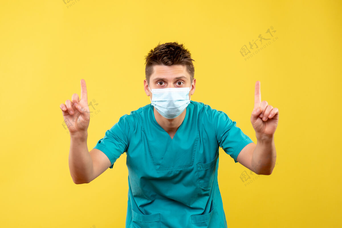 疾病黄色墙上穿着医疗服 戴着防护面具的男医生的正视图西装病毒医疗