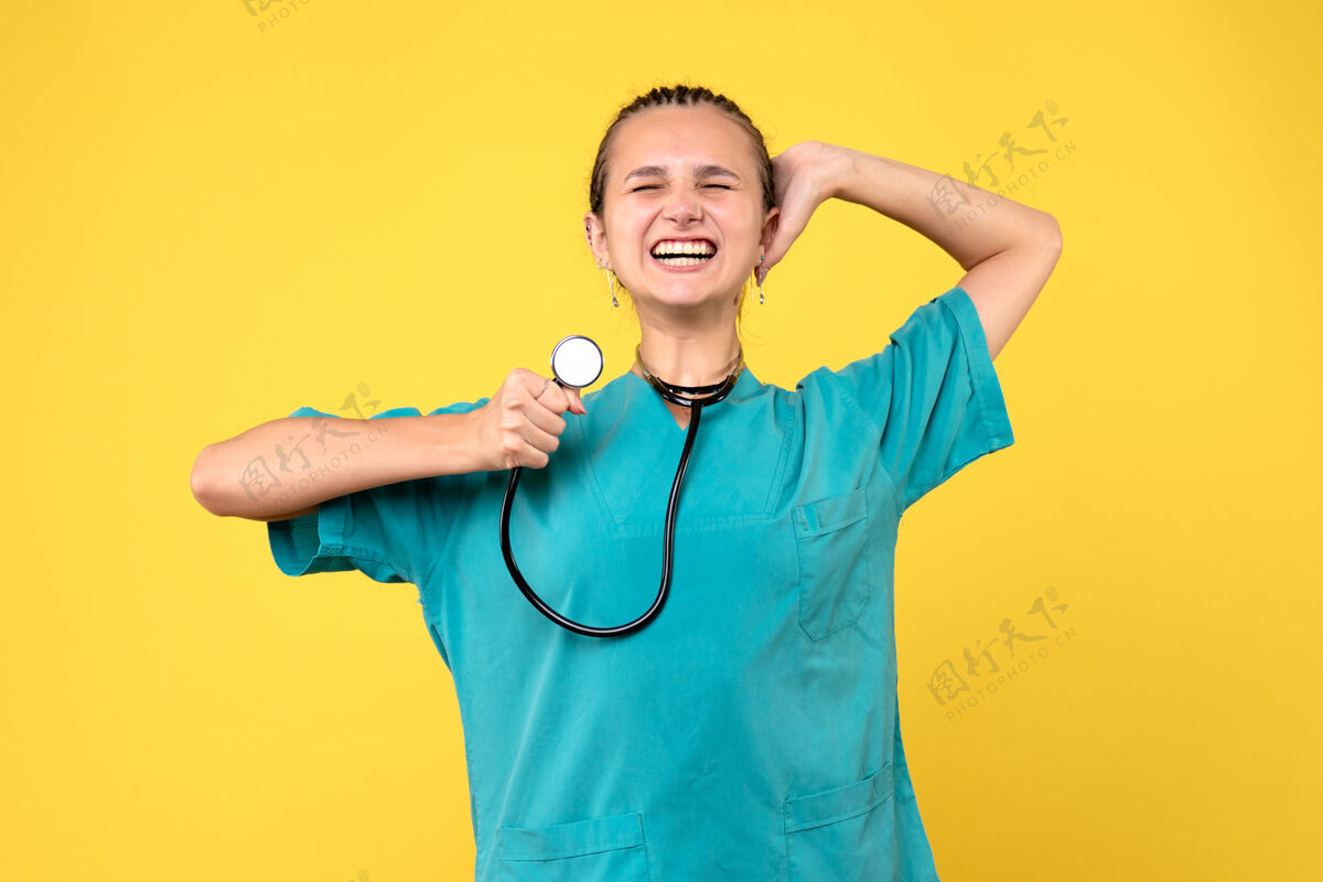医疗仪器黄色墙壁上穿着医疗服的女医生的正视图女人人女医生
