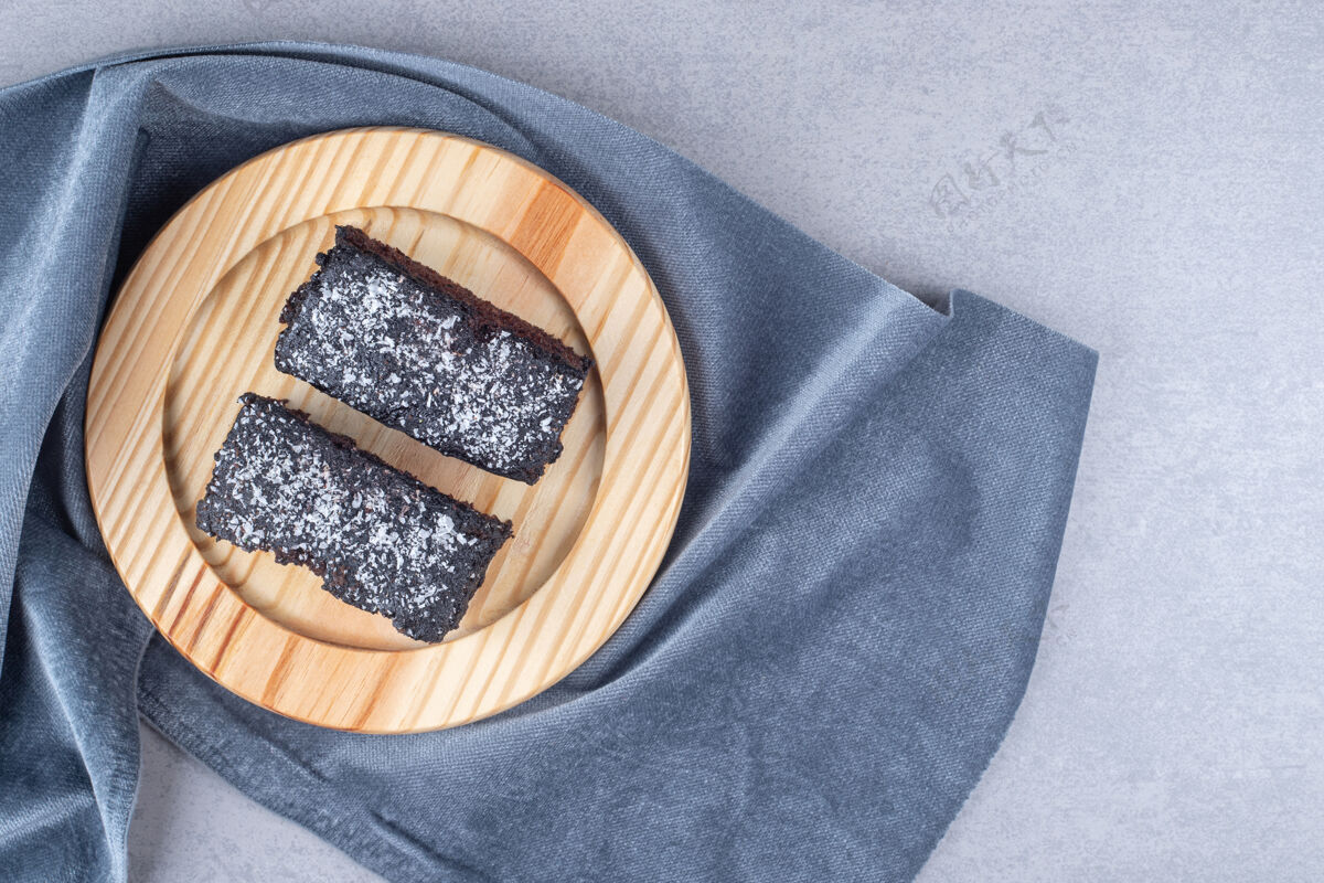 美味巧克力蛋糕片放在大理石桌上的毛巾上的木盘上巧克力蛋糕糕点