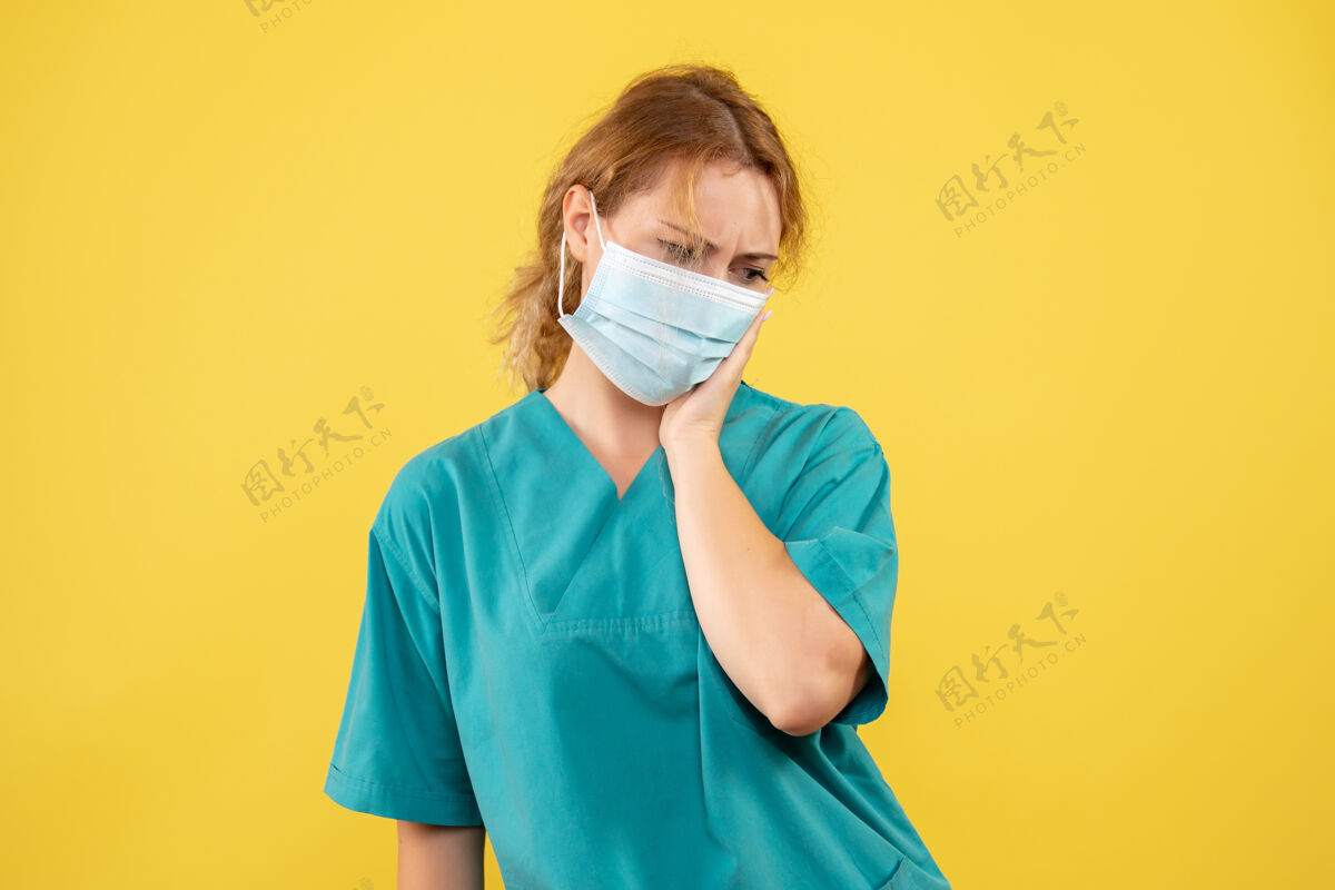 女医生黄色墙壁上穿着医疗服 戴着口罩的女医生的正视图约束医疗肖像