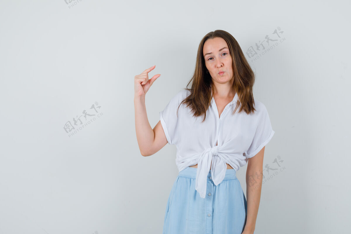 健康年轻的女士展示了小尺寸标志的衬衫和裙子 看起来很自信前面裙子信心