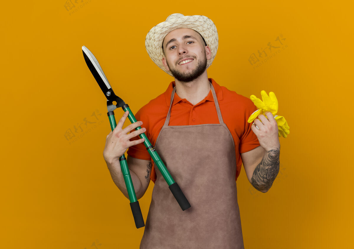 剪子微笑的男园丁戴着园艺帽拿着剪刀和手套花园微笑穿