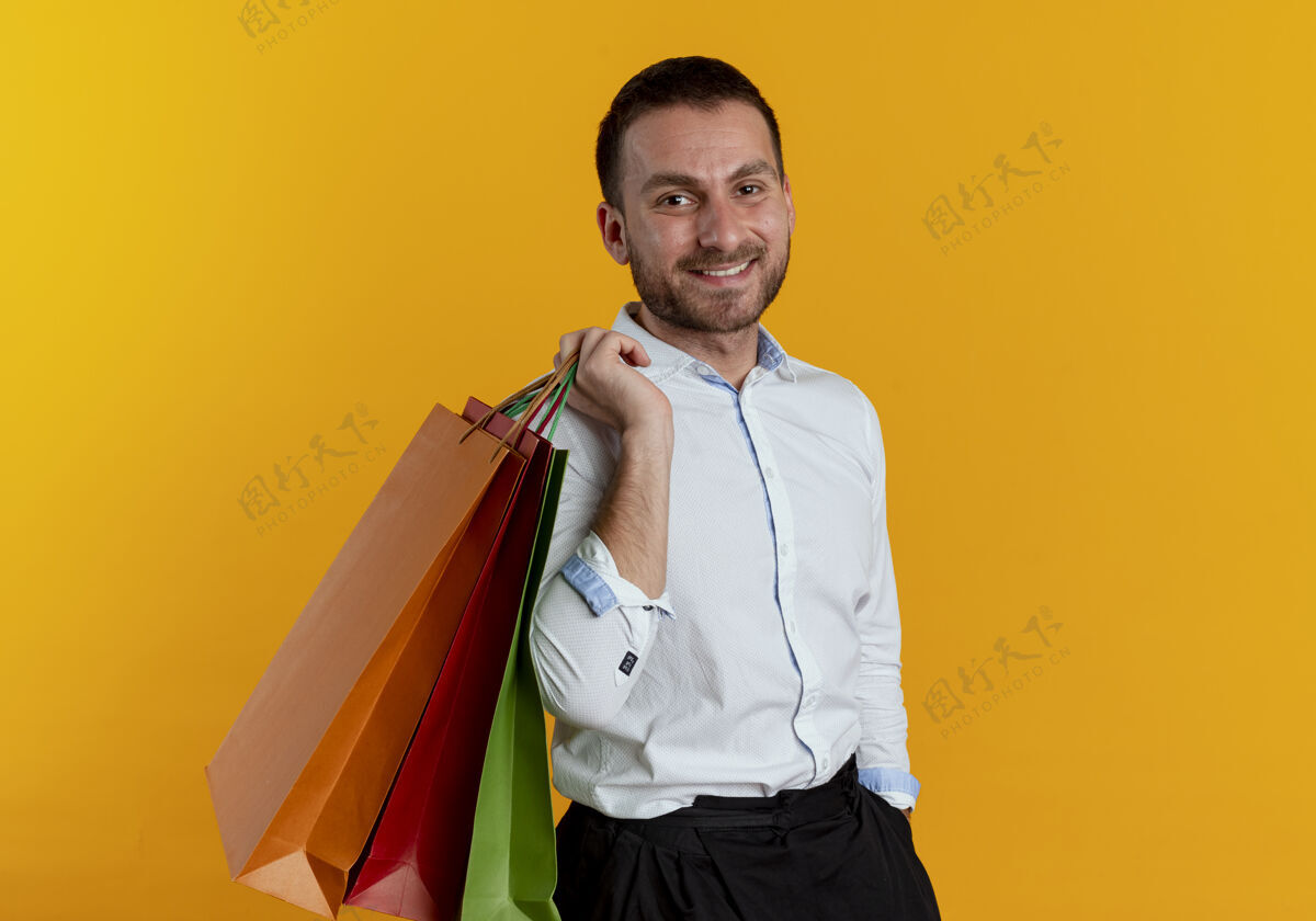 抱着笑容可掬的帅哥肩上扛着纸质购物袋 在橘色的墙上显得孤立无援微笑包人